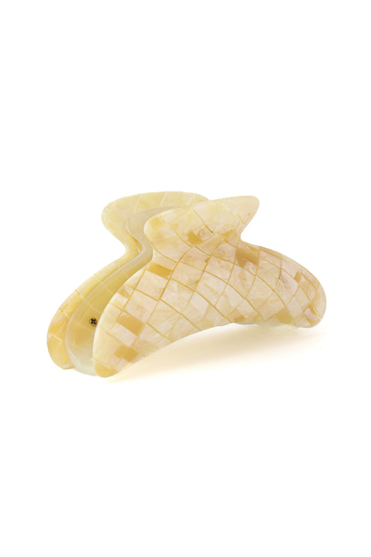 A single cream-colored hair claw clip with a textured, grid-like pattern on the outer surface, shown on a plain white background.