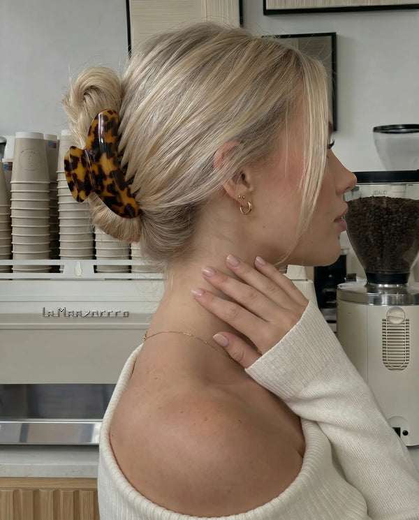 Woman with styled hair in a coffee shop wearing. tortoise coloured claw clip.